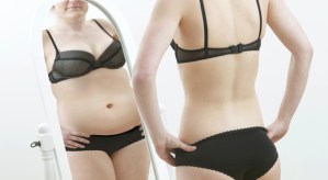 Slim girl looking at fat reflection in mirror